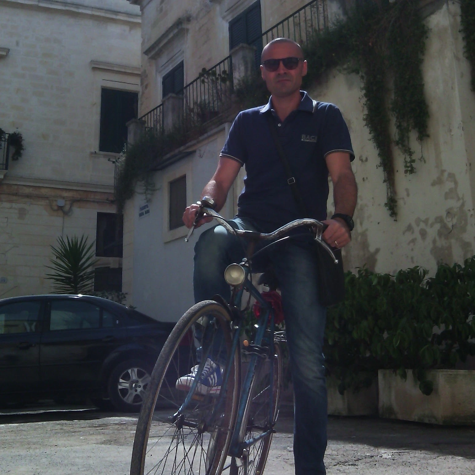 Stefano Spagnolo riding a vintage bicycle through a historic Italian city center